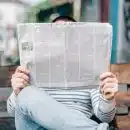 une personne lisant un journal sur un banc