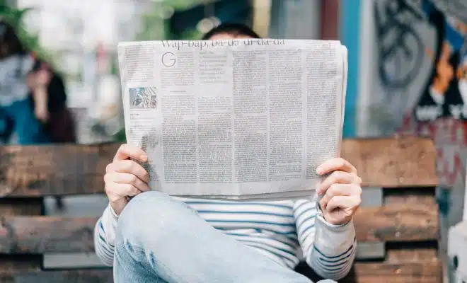 une personne lisant un journal sur un banc